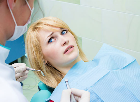 Woman in dental chair looking apprehensive