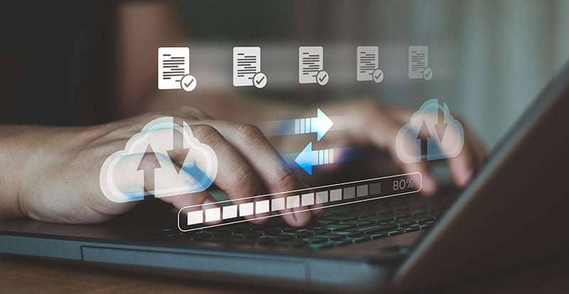 photo of a person at a computer with icons overlapping showing files transferring